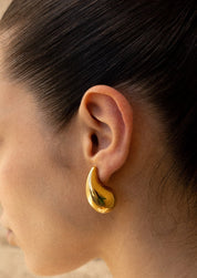 Gold teardrop earrings on model, close-up ear detail