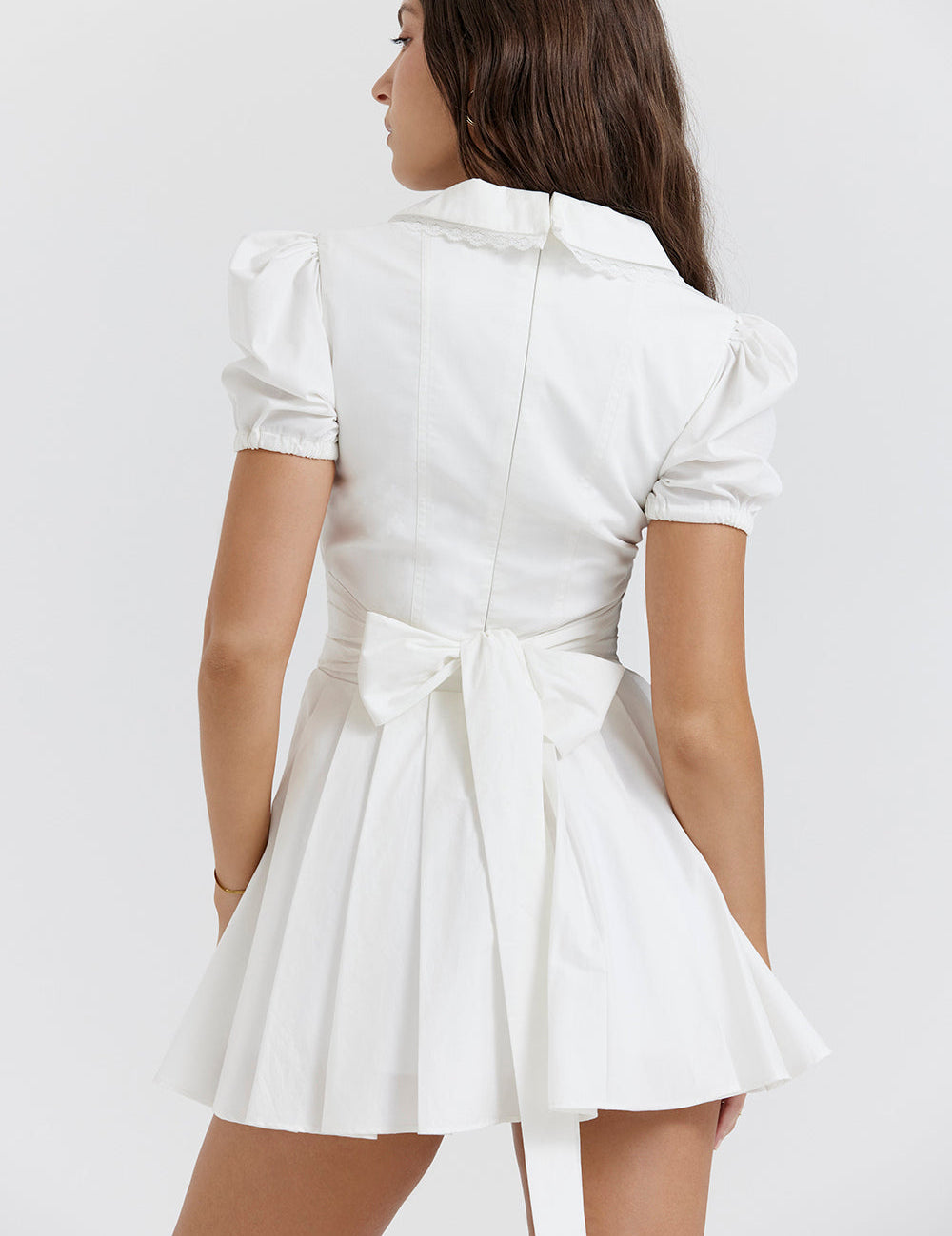 White mini dress with V-neck and pleated skirt back view