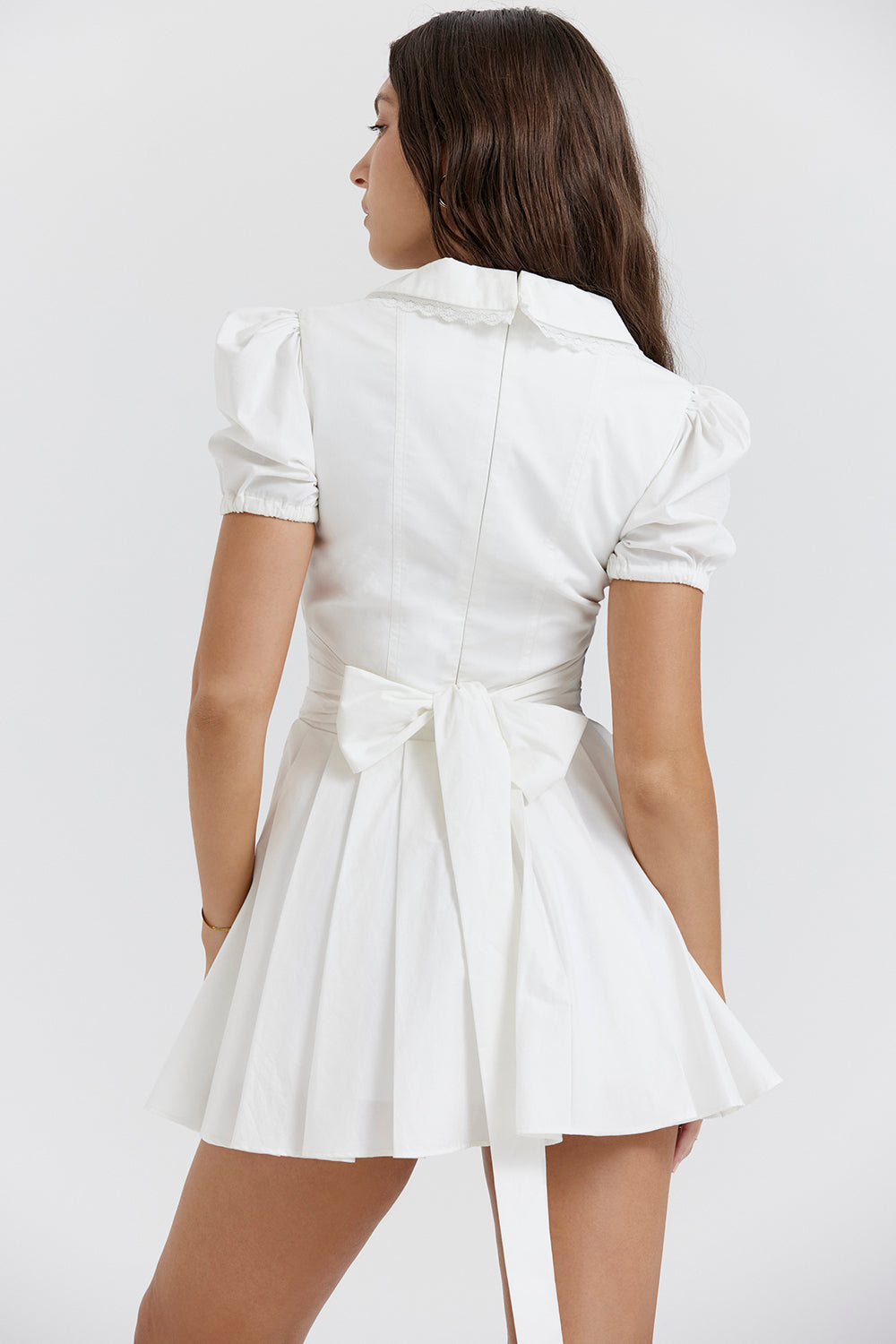 White mini dress with V-neck and pleated skirt back view
