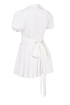 White mini dress with V-neck and pleated skirt isolated side view