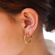 Gold hoop earrings worn on ear, close-up detail