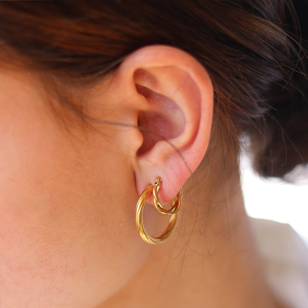 Gold hoop earrings worn on ear, close-up detail