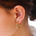 Gold hoop earrings worn on ear, close-up detail