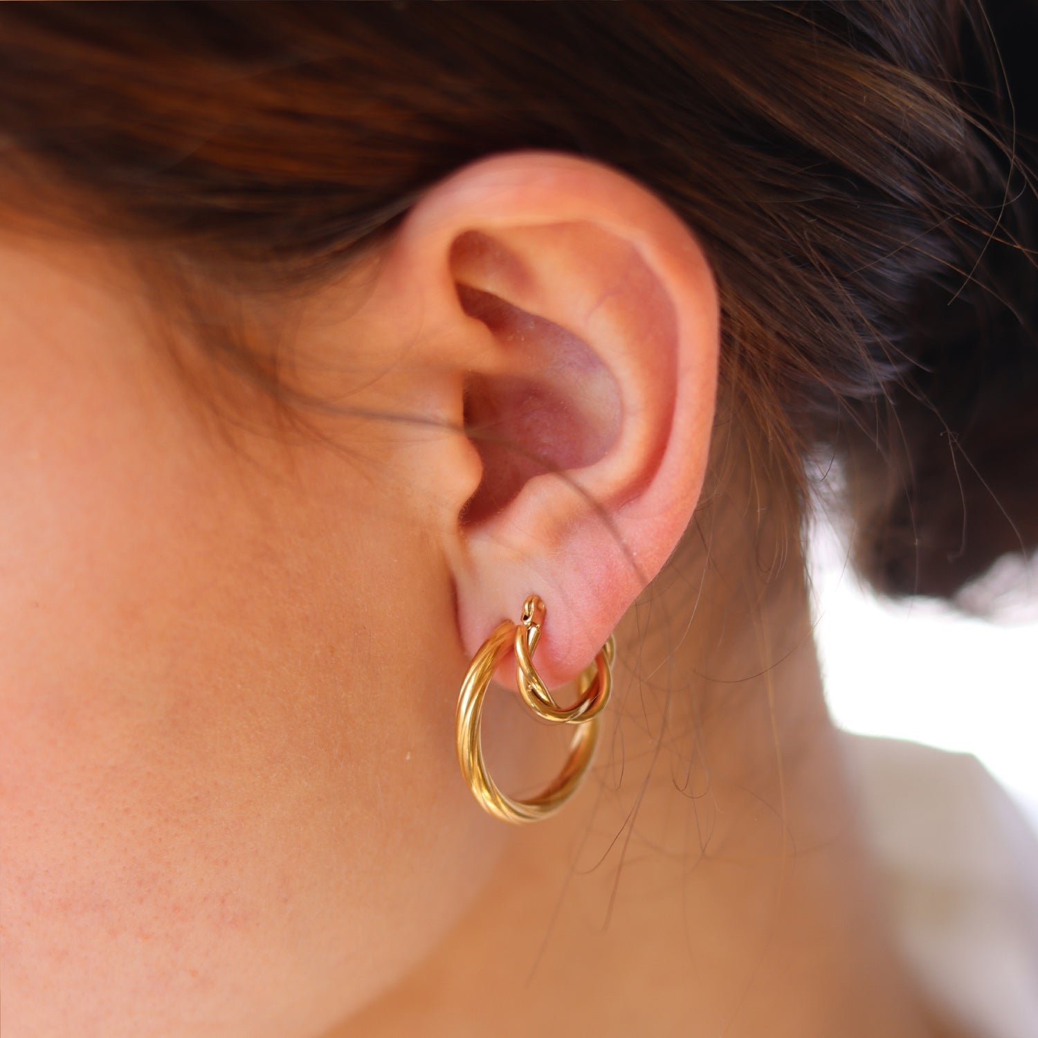 Gold hoop earrings worn on ear, close-up detail