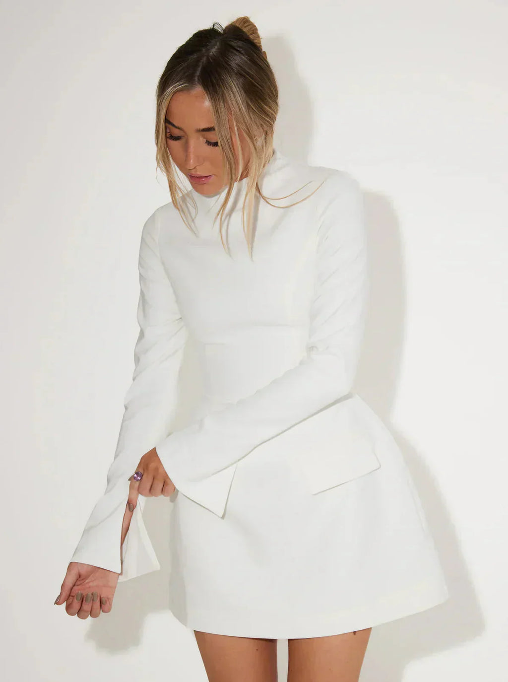Mini jurk witte stof met hoge hals en flared mouwen, zij profiel