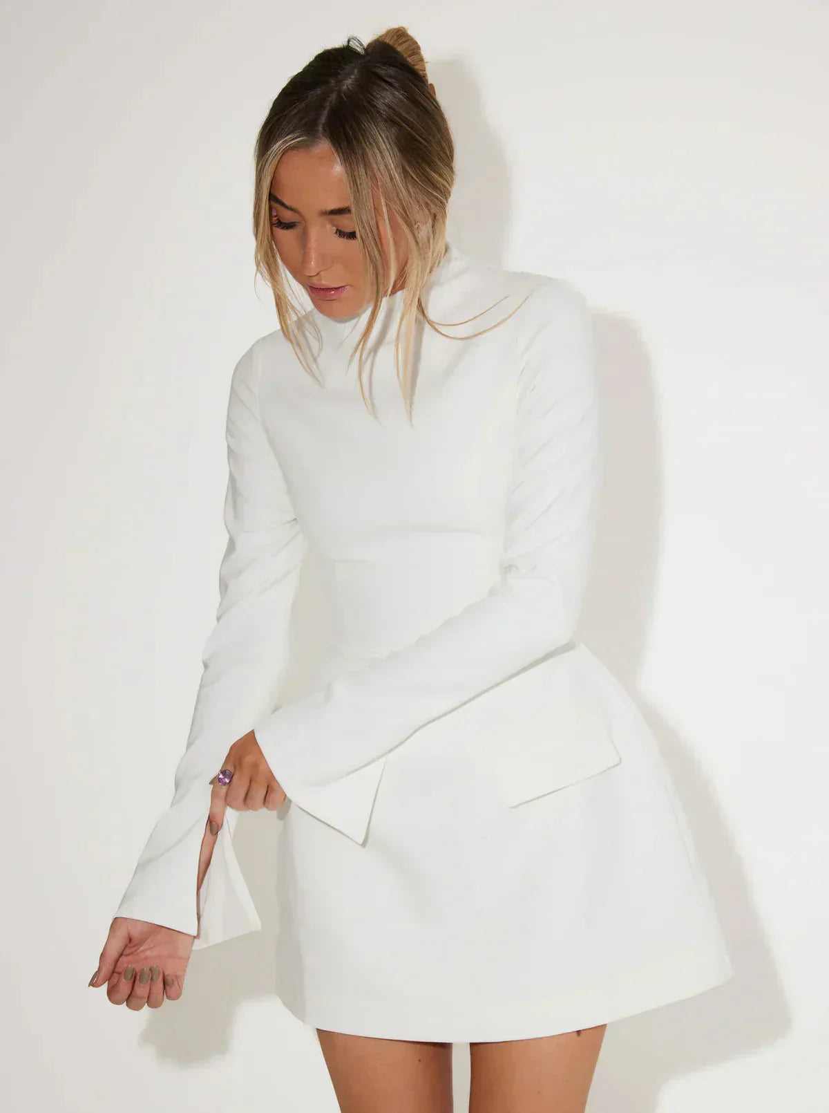 Mini jurk witte stof met hoge hals en flared mouwen, zij profiel