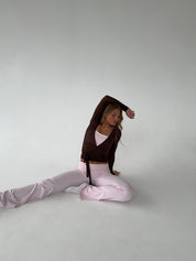 Brown wrap top with pink pants seated pose