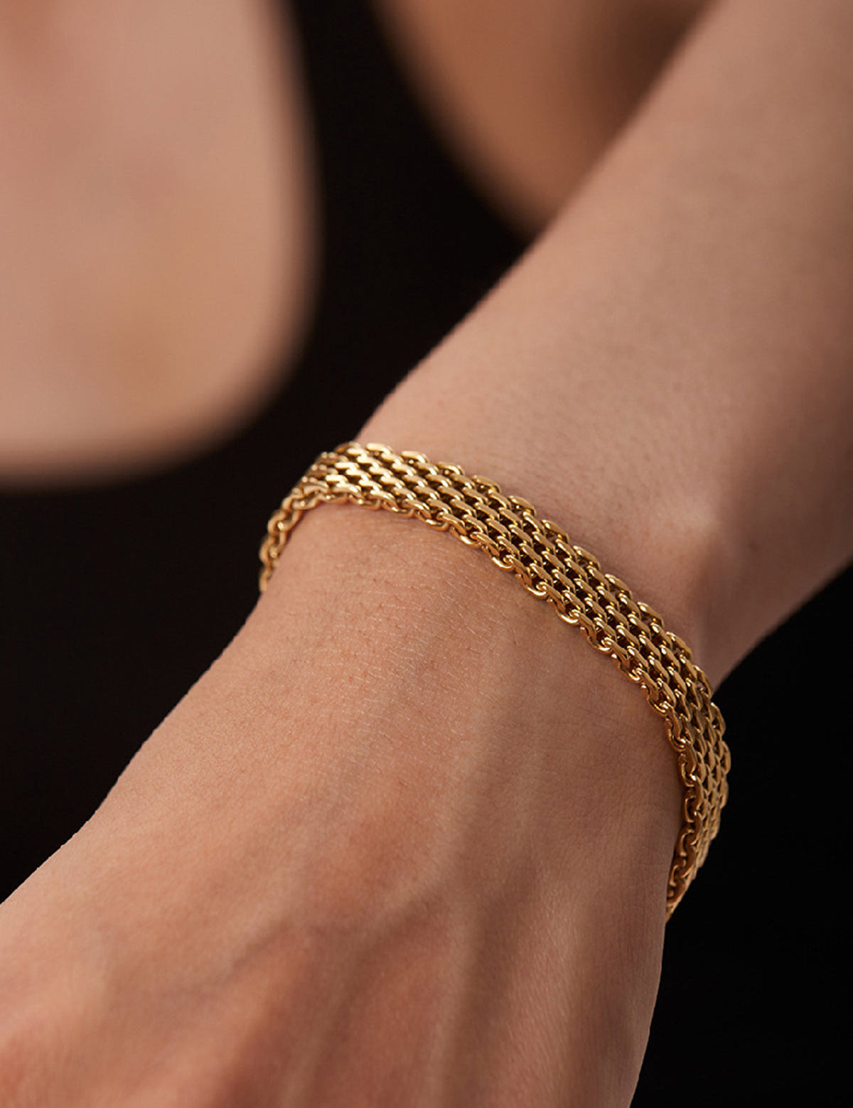 Gold multi-strand woven bracelet on wrist close-up