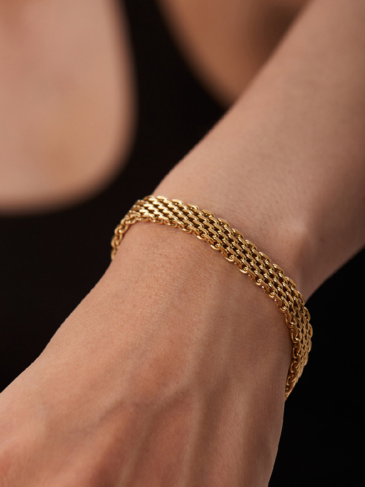 Gold multi-strand woven bracelet on wrist close-up