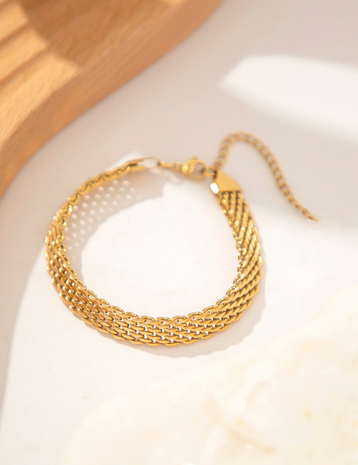 Gold multi-strand woven bracelet on white surface front view