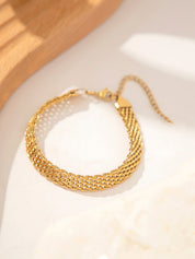 Gold multi-strand woven bracelet on white surface front view