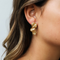 Gold hammered organic multi-disc cascade earrings on ear