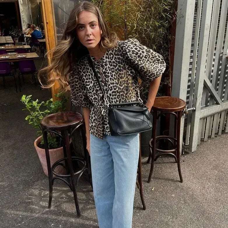 Leopard print blouse paired with light blue jeans and black crossbody bag, front view