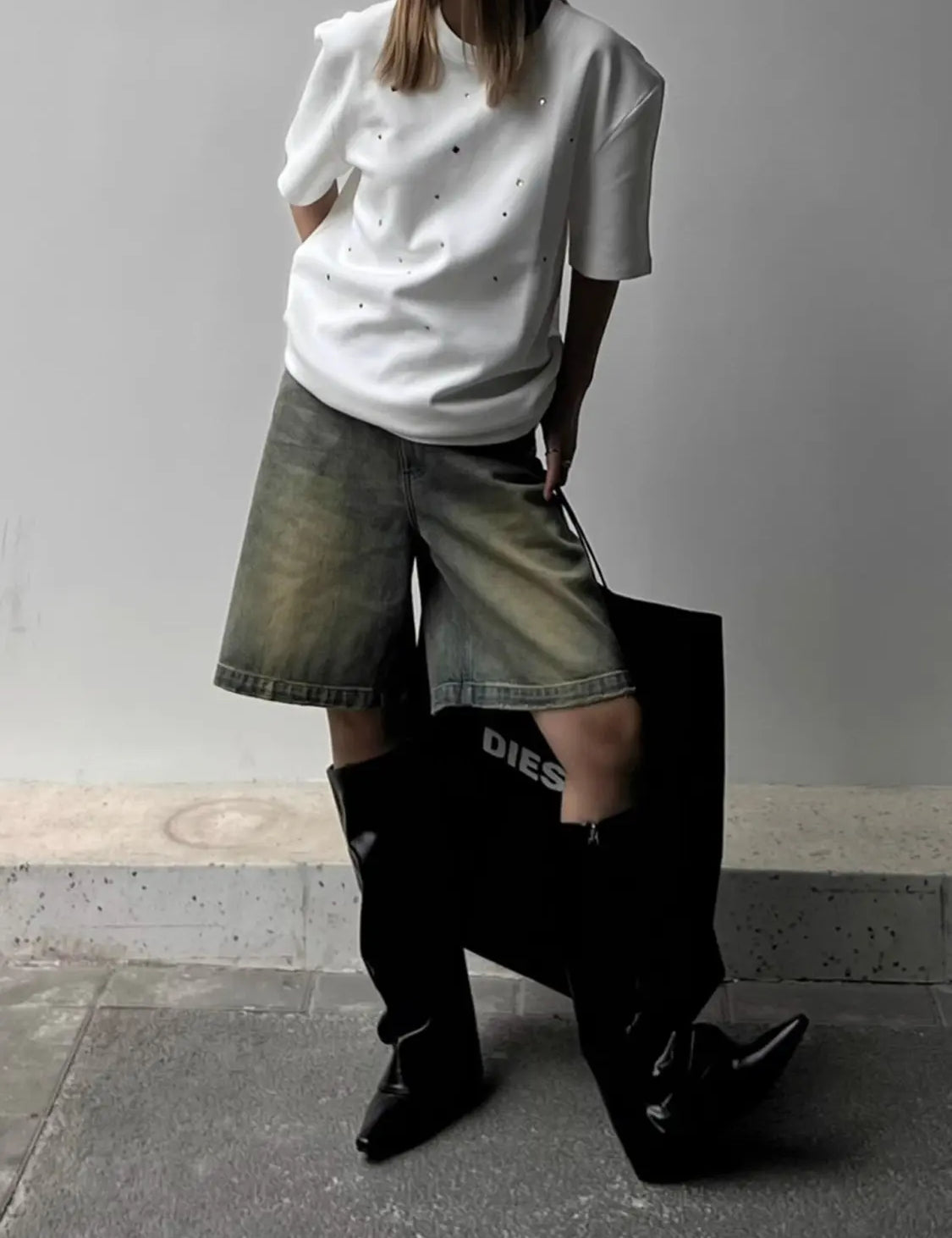 White t-shirt with glittery rhinestones worn with denim shorts and black boots, side view