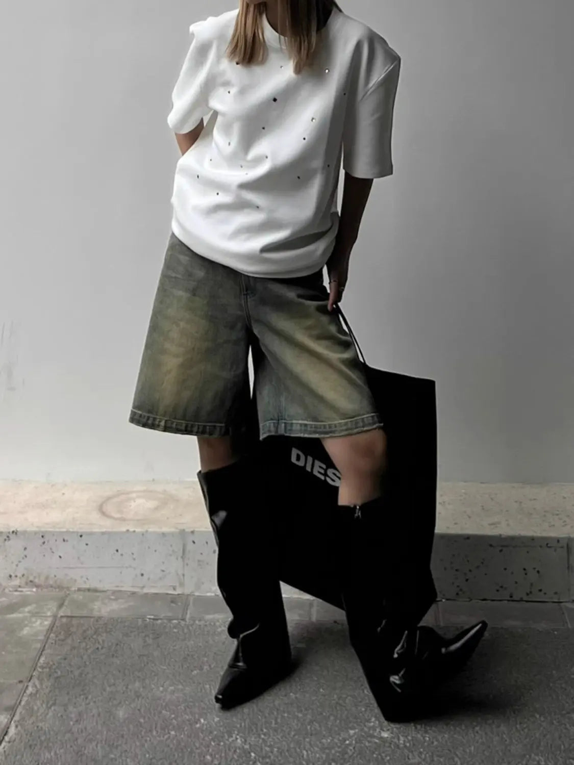 White t-shirt with glittery rhinestones worn with denim shorts and black boots, side view