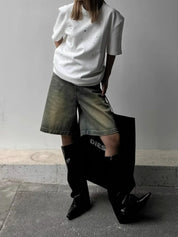 White t-shirt with glittery rhinestones worn with denim shorts and black boots, side view
