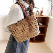 Woven straw tote bag with brown leather handles, front view with model and shelf