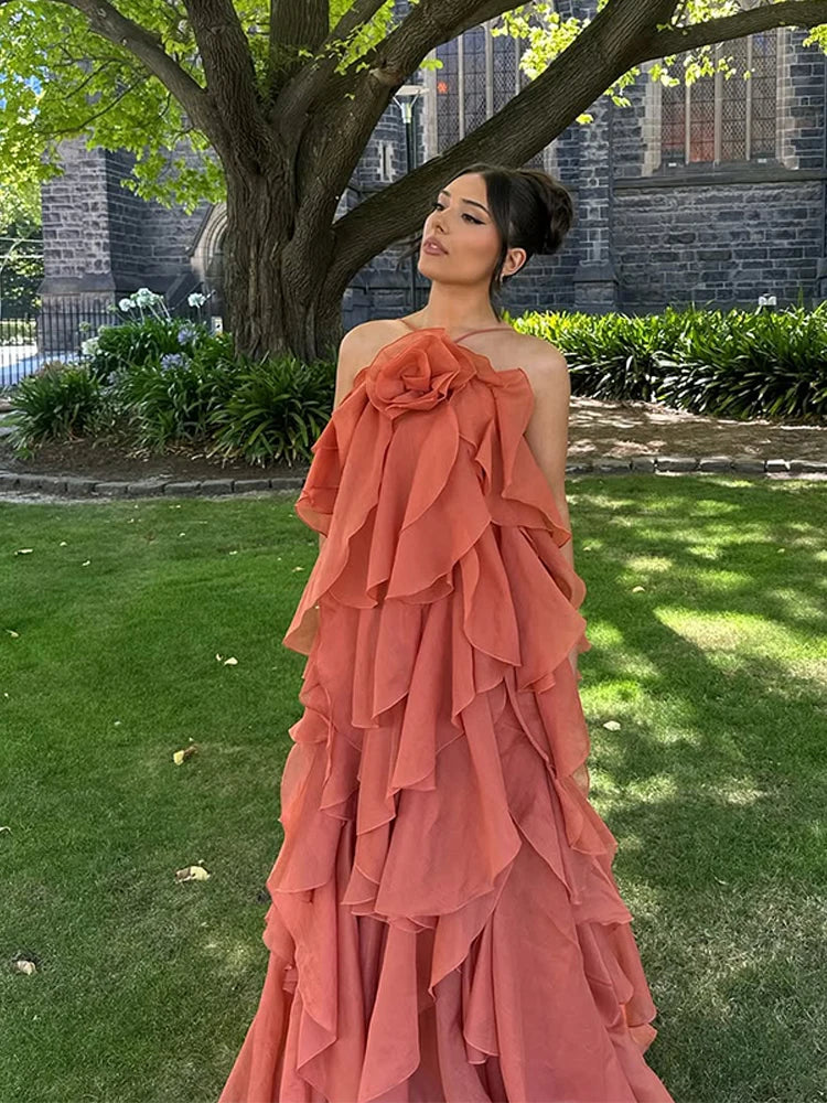 Orange maxi dress with ruffles, outdoor front view against greenery