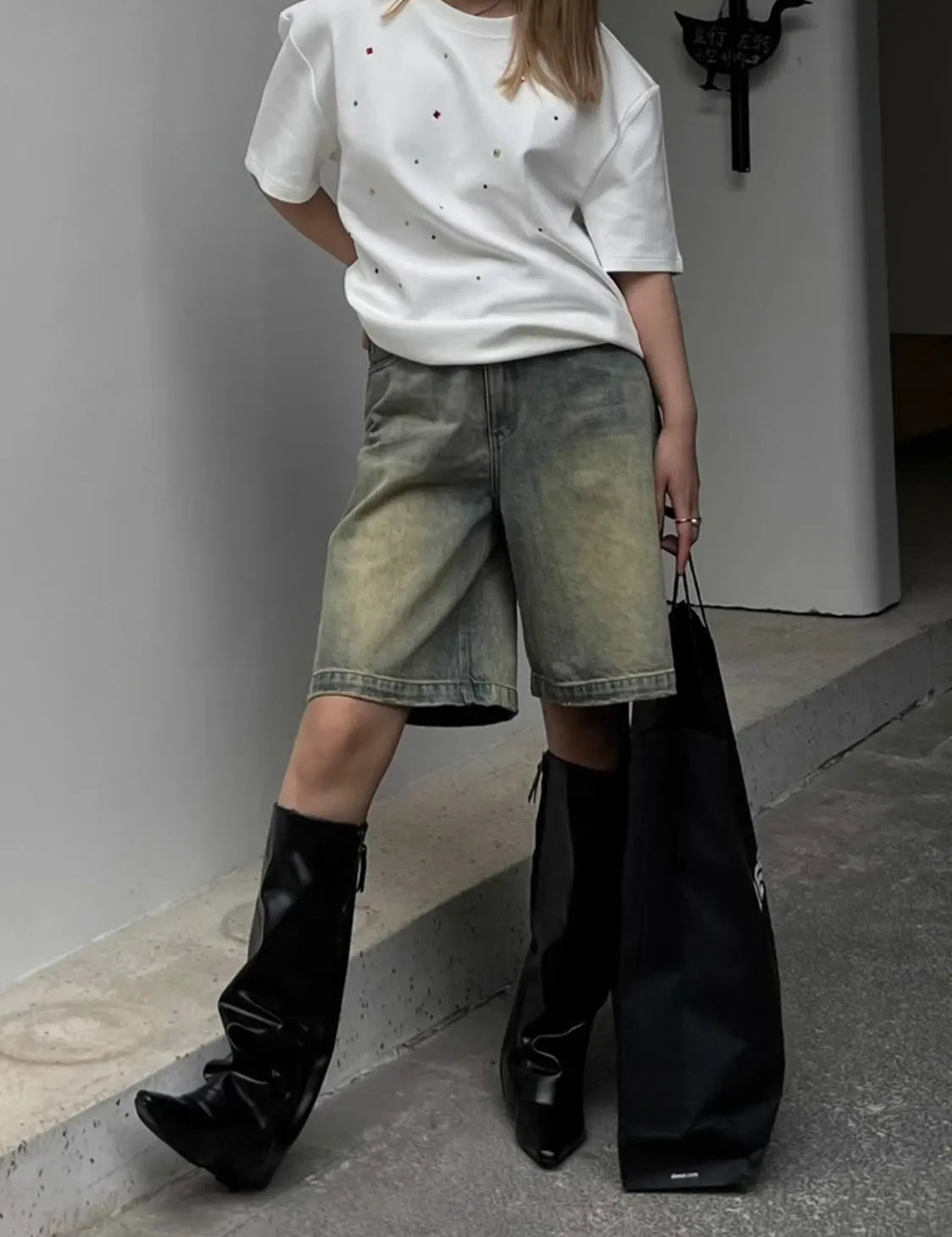 White t-shirt with glittery rhinestones worn with denim shorts and black boots, front view