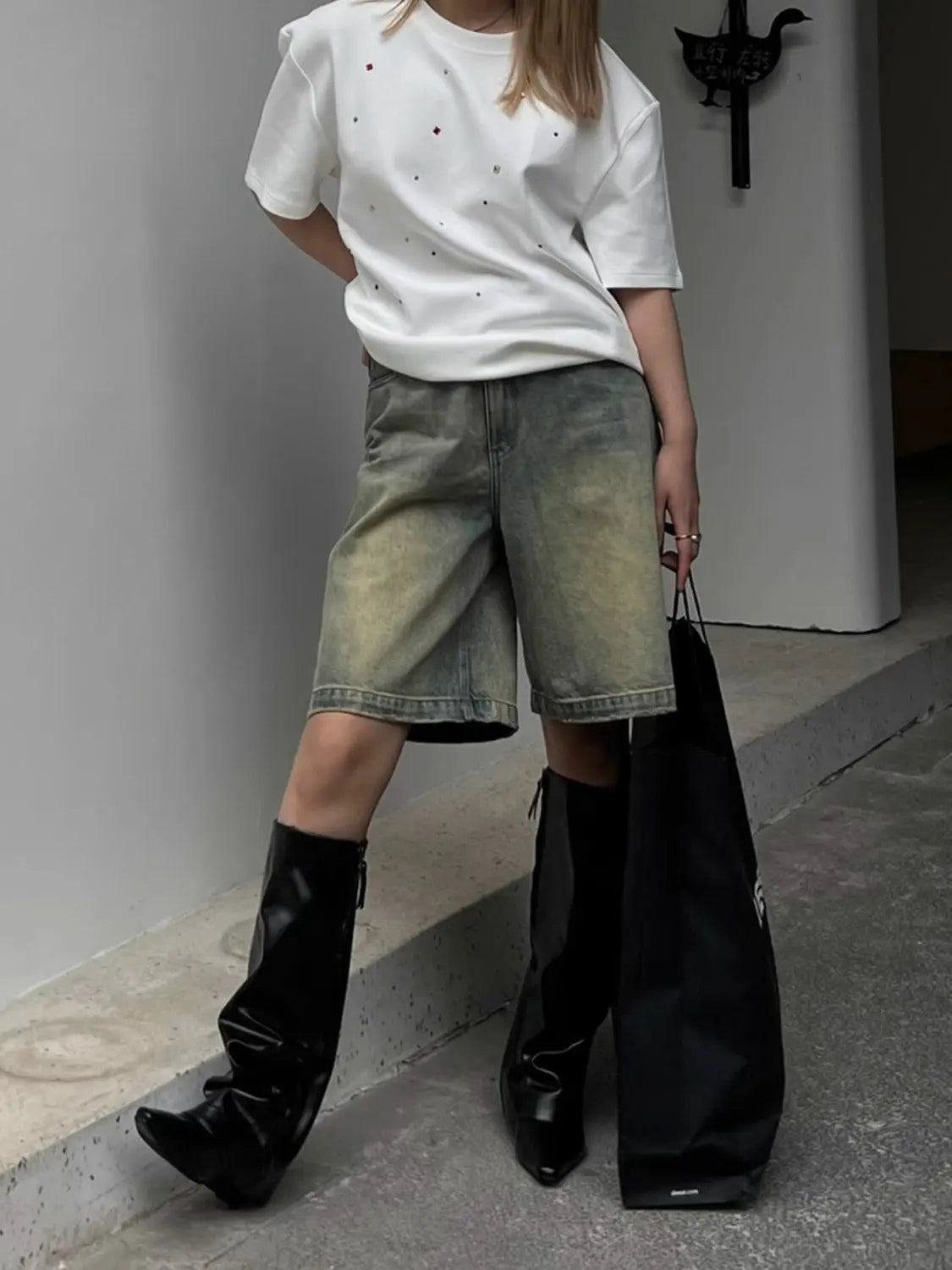 White t-shirt with glittery rhinestones worn with denim shorts and black boots, front view