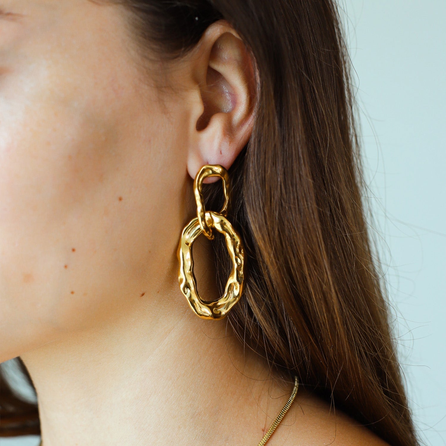 Gold-plated double-link hoop earrings worn on ear side view