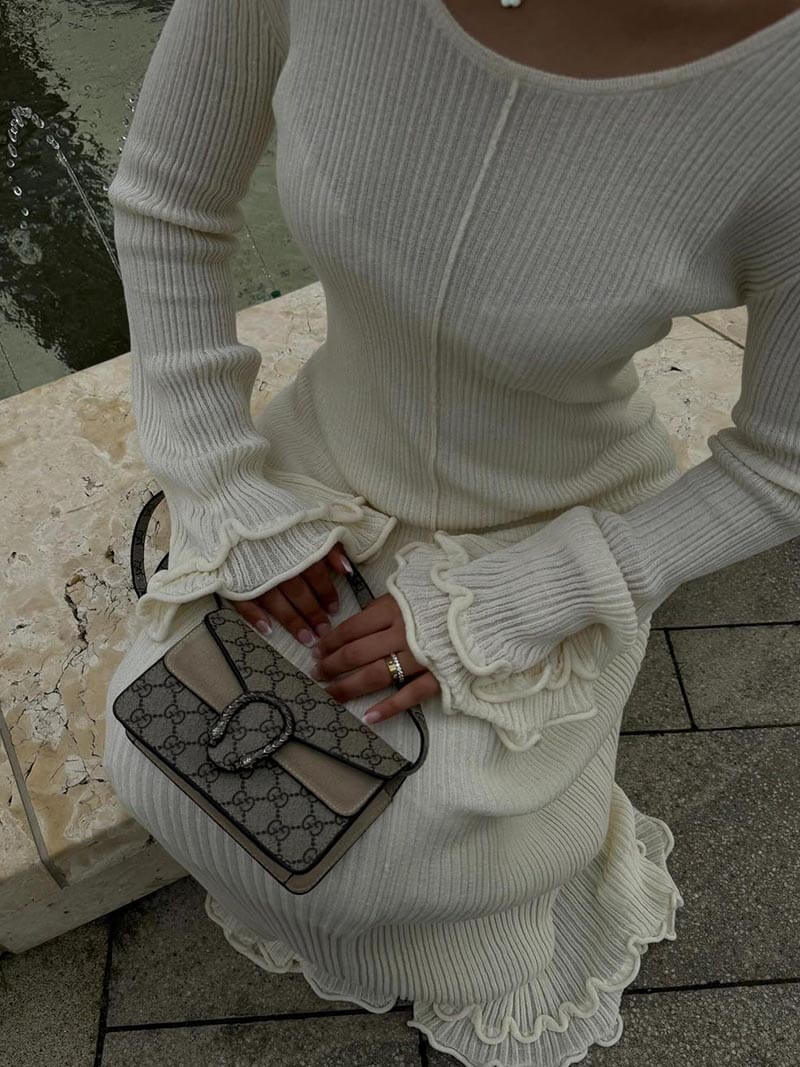 Close-up of white maxi dress with ruffled sleeves and pleated skirt