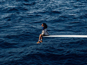 Person wearing sweatshirt with 'SZA' and '5', blue and white, seated by water