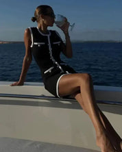 Black dress with white contrast trim and buttons, front view on a boat, elevated angle