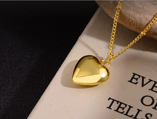 Gold heart pendant necklace on chain resting on book detail shot