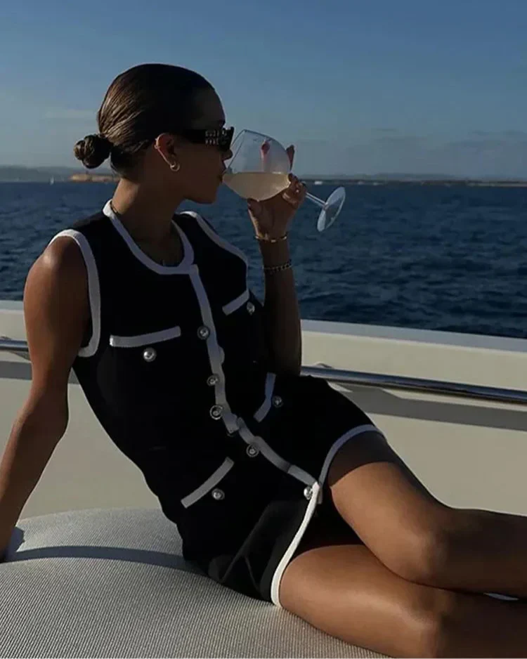 Black dress with white contrast trim and buttons, front view on a boat