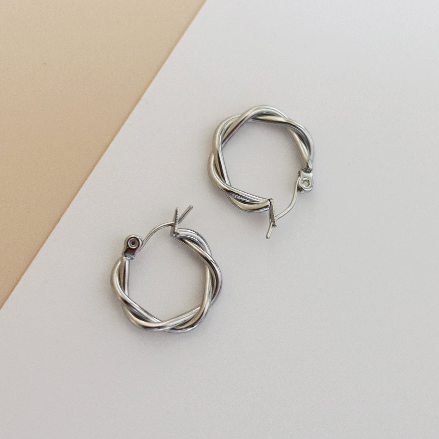 Silver hoop earrings with twisted design, angled view