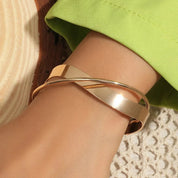 Gold armband with layered metal design, angled view