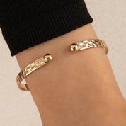 Gold armband with textured and ball detail, front view