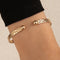 Gold armband with textured and ball detail, front view