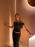 Black top with white polka dots and asymmetrical sleeve three-quarter view