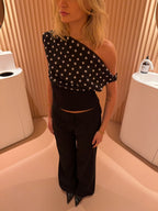Black top with white polka dots and asymmetrical sleeve close-up detail