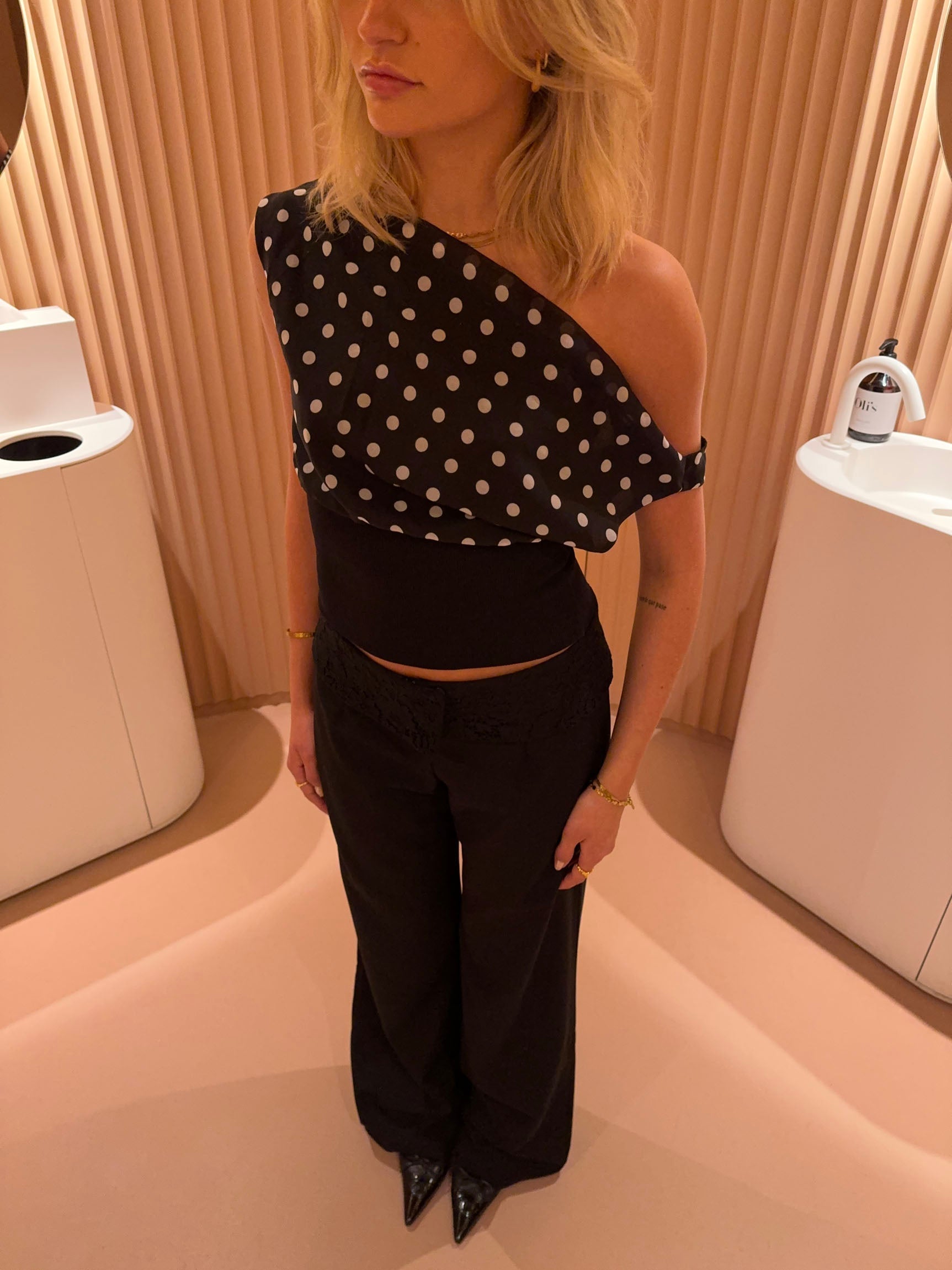 Black top with white polka dots and asymmetrical sleeve close-up detail