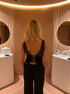 Black top with white polka dots and asymmetrical sleeve back view