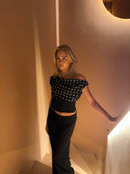 Black top with white polka dots and asymmetrical sleeve three-quarter view