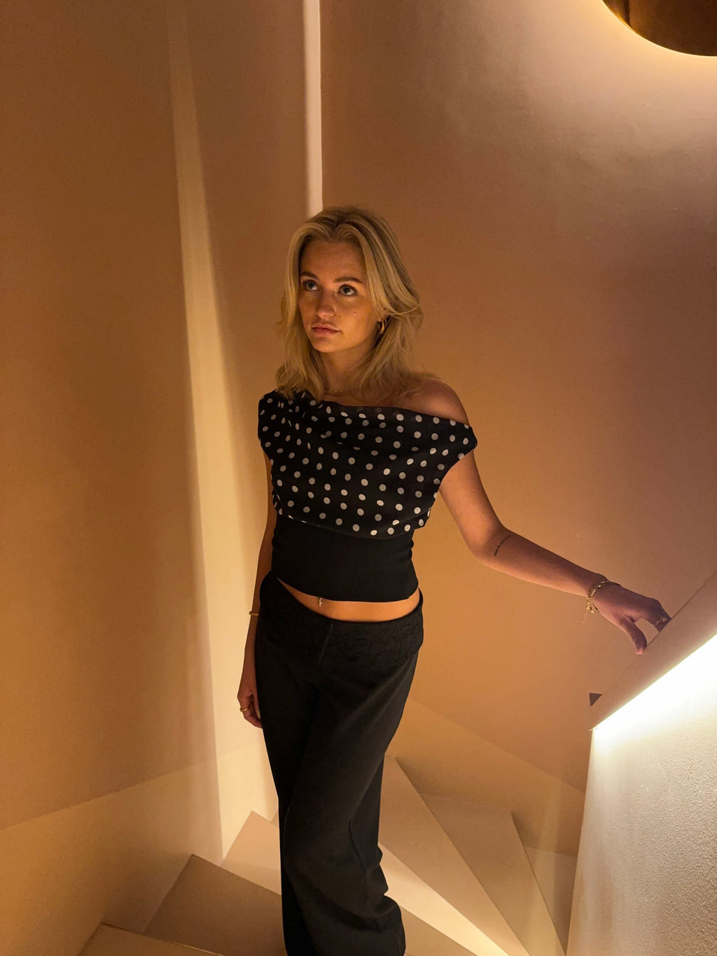 Black top with white polka dots and asymmetrical sleeve side profile