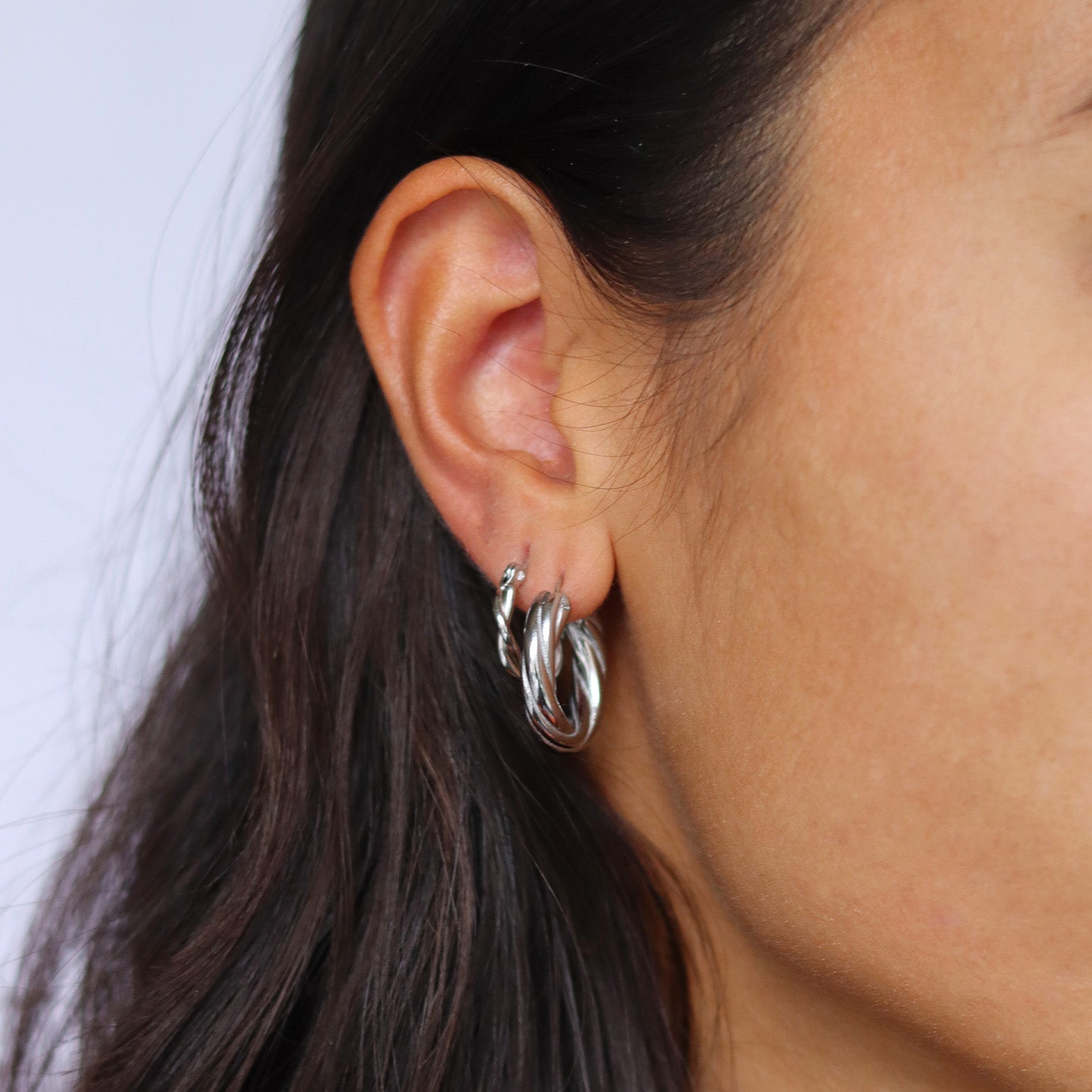Silver hoop earrings worn on ear, side view