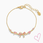 Gold necklace with pink heart stones and bow detail, front view