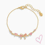 Gold necklace with pink heart stones and bow detail, front view