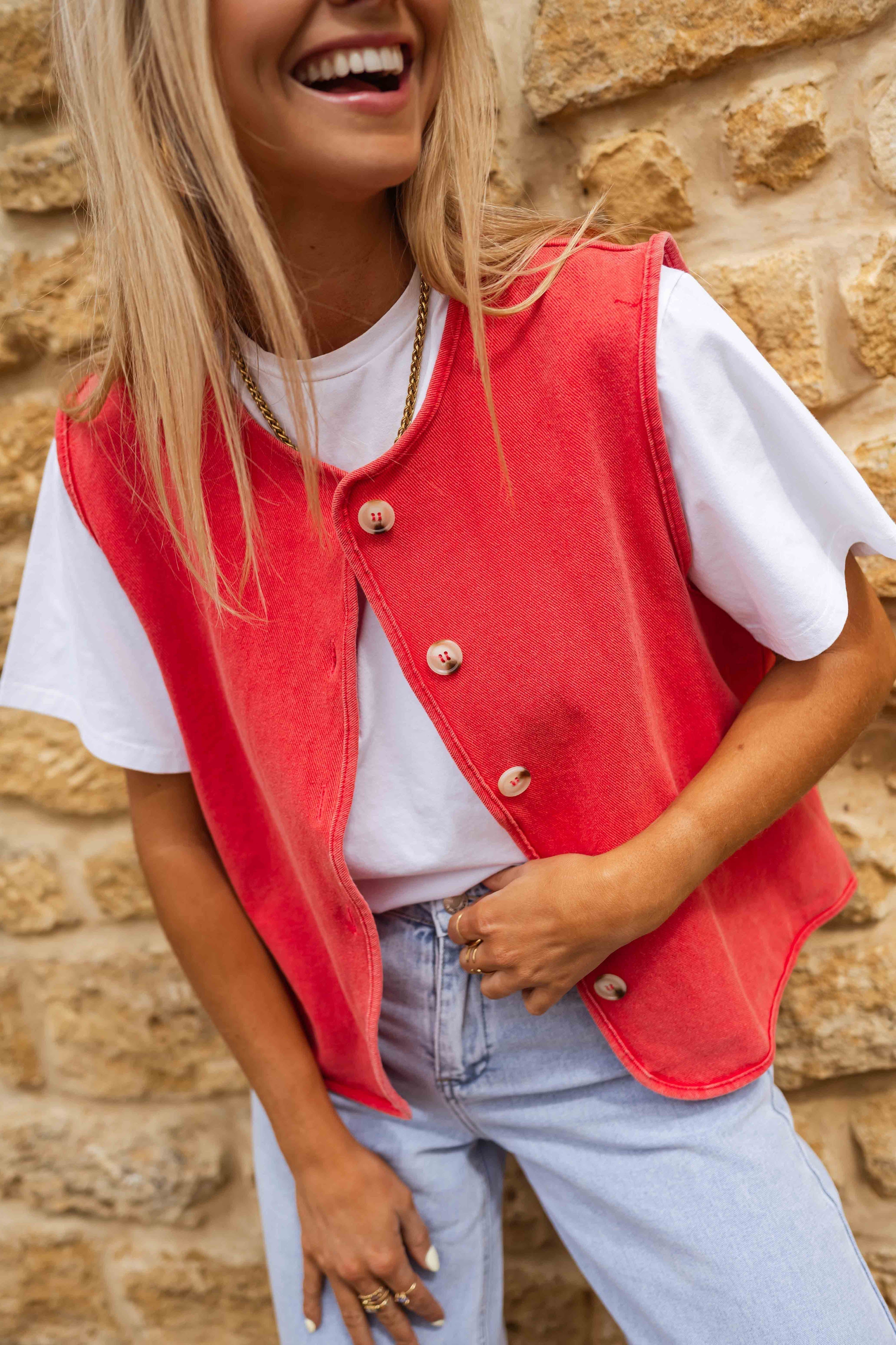 Red sleeveless gilet with buttons close-up detail