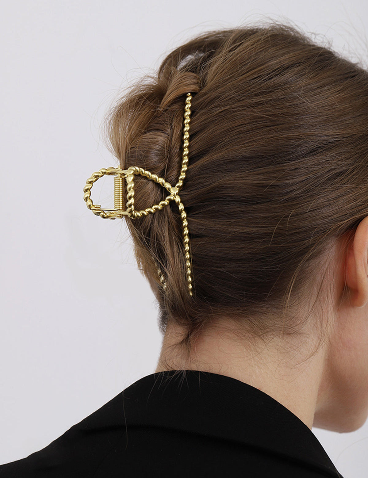 Gold metal hair clamp with twisted texture, side view on hair