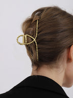 Gold metal hair clamp with twisted texture, side view on hair