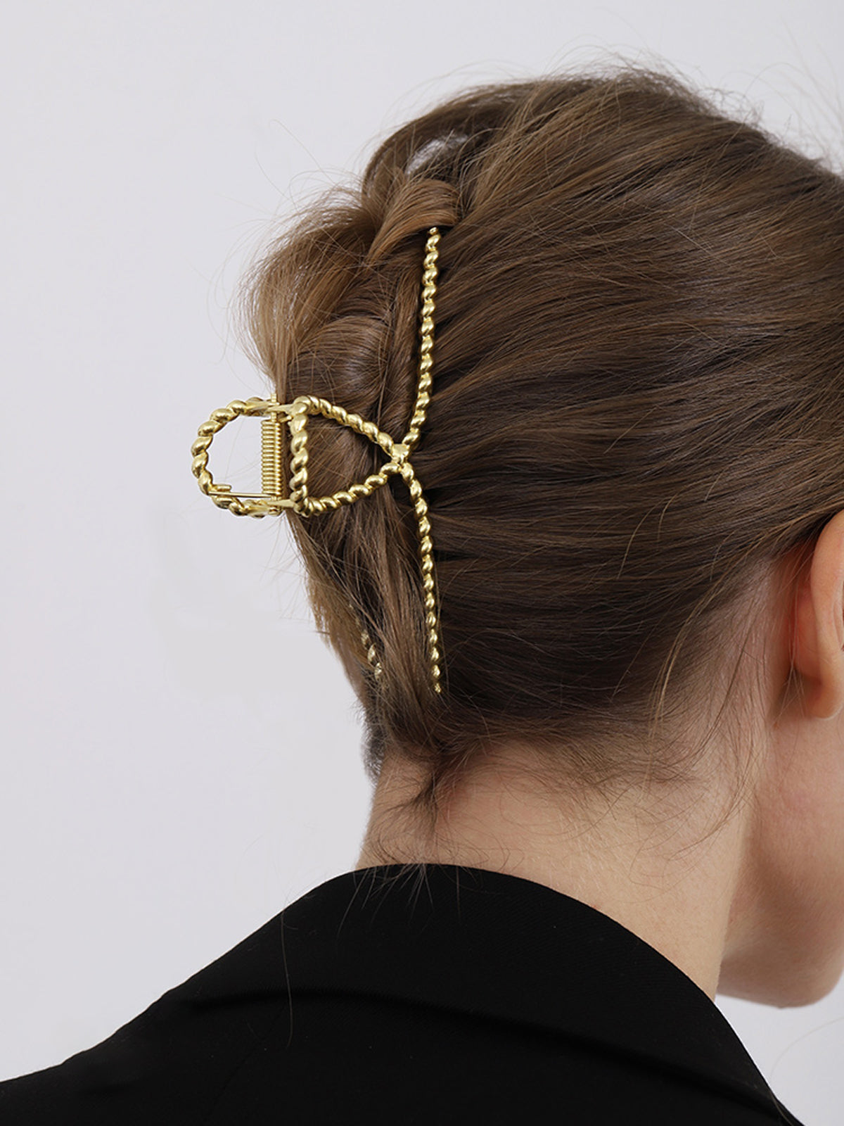 Gold metal hair clamp with twisted texture, side view on hair