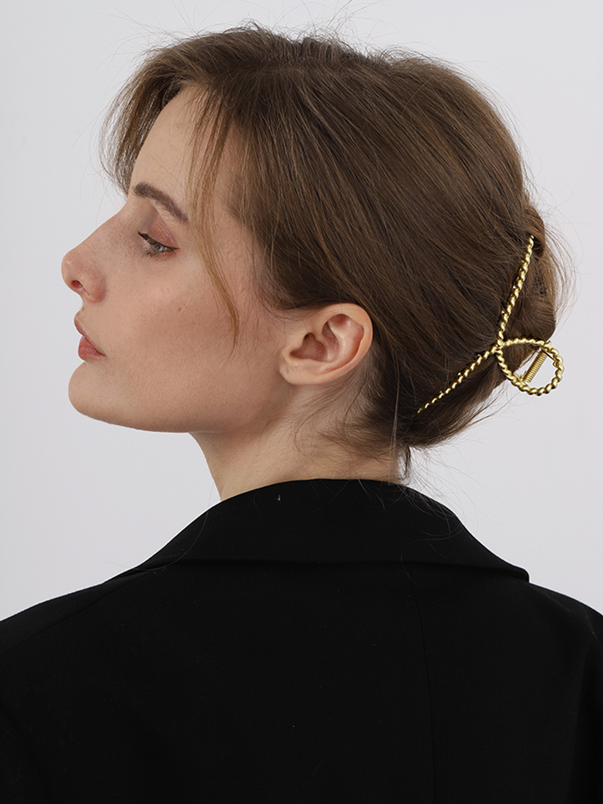Gold metal hair clamp with twisted texture, side view on styled hair