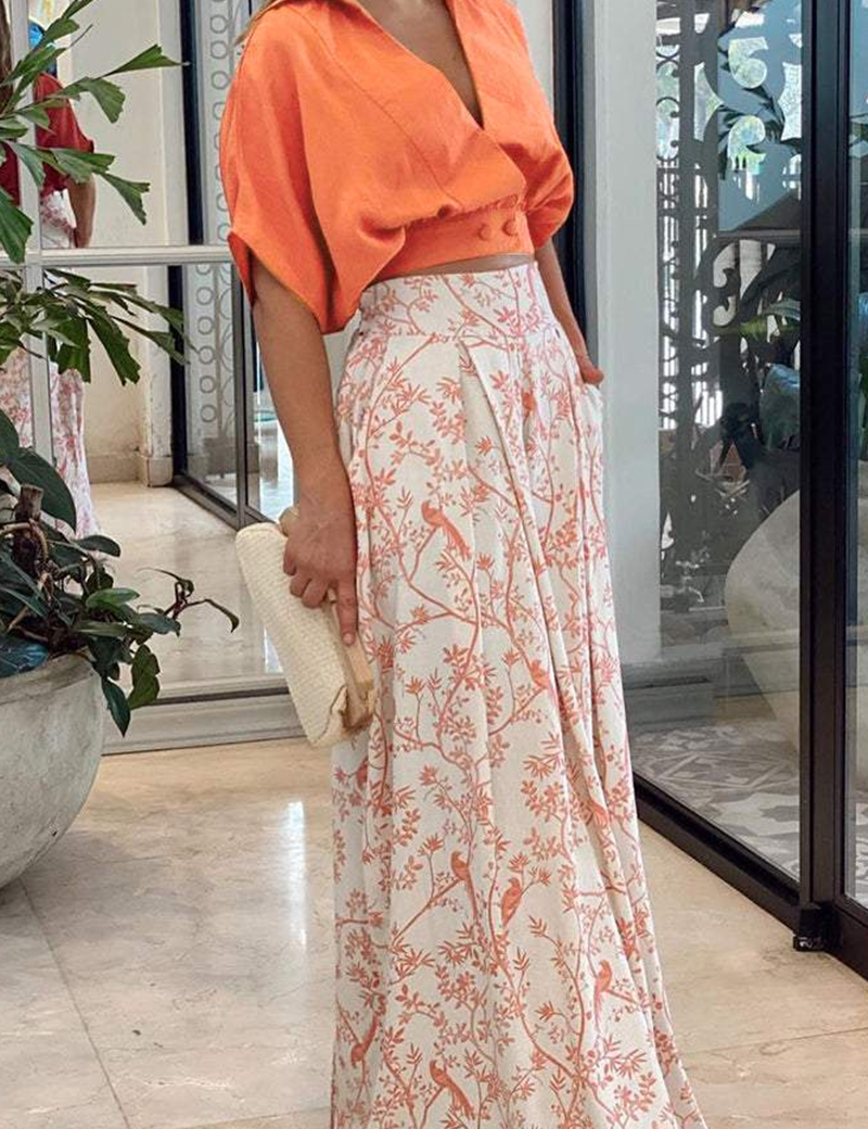 Orange crop top and white pants with bird print, front view