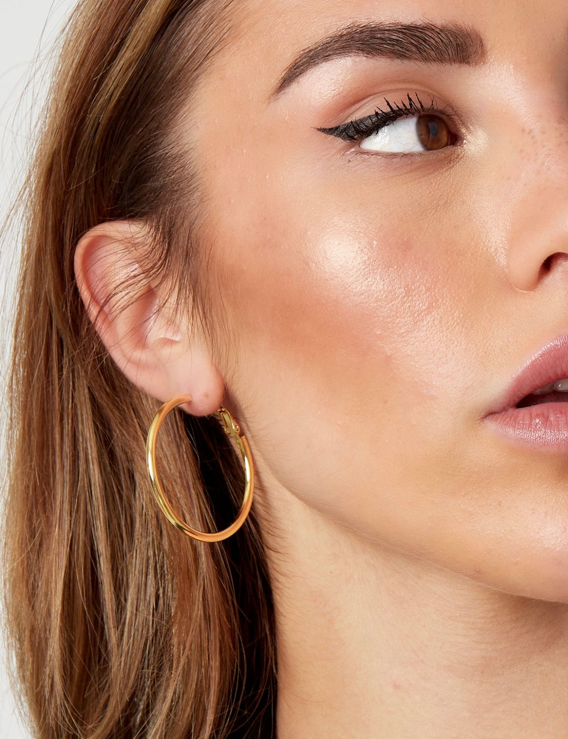 Gold hoop earrings worn on ear close-up